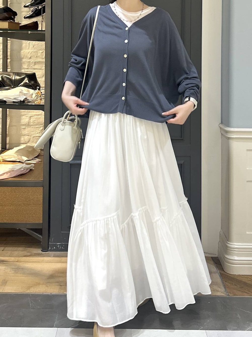 グレー系のカーディガン/ボレロ、ホワイト系のスカート、ホワイト系のTシャツ/カットソーを着用したレディースの夏コーディネートの4枚目の写真