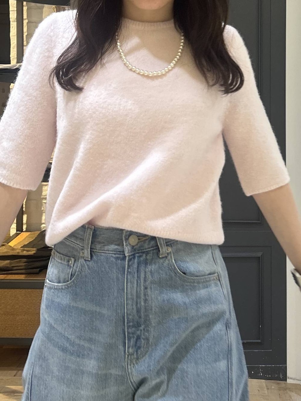 ホワイト系のショルダーバッグ、ブルー系のデニムパンツ、ブラック系のパンプスを着用したレディースの秋コーディネートの5枚目の写真
