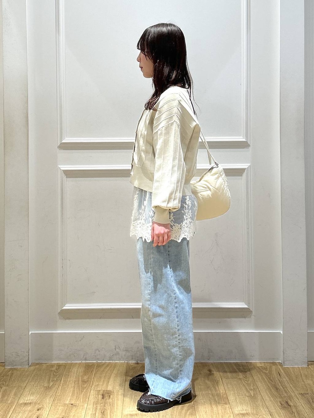 ベージュ系のカーディガン/ボレロ、ホワイト系のキャミソール、ブルー系のデニムパンツを着用したレディースの春コーディネートの2枚目の写真