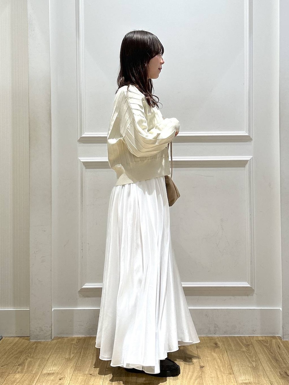 ベージュ系のカーディガン/ボレロ、ホワイト系のスカート、ブラウン系のローファーを着用したレディースの春コーディネートの2枚目の写真