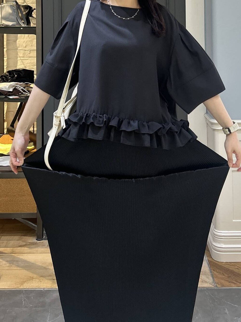 ホワイト系のショルダーバッグ、ブラック系のスカート、ブラック系のパンプスを着用したレディースの夏コーディネートの5枚目の写真