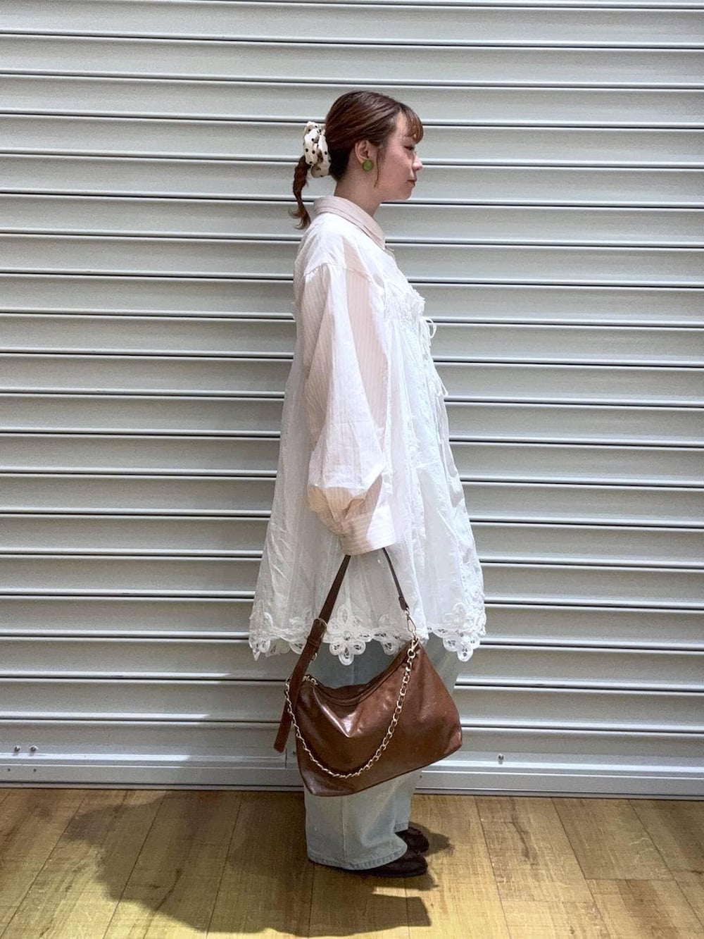 ブルー系のデニムパンツ、ブラウン系のショルダーバッグ、ピンク系のシャツ/ブラウスを着用したレディースの春コーディネートの2枚目の写真