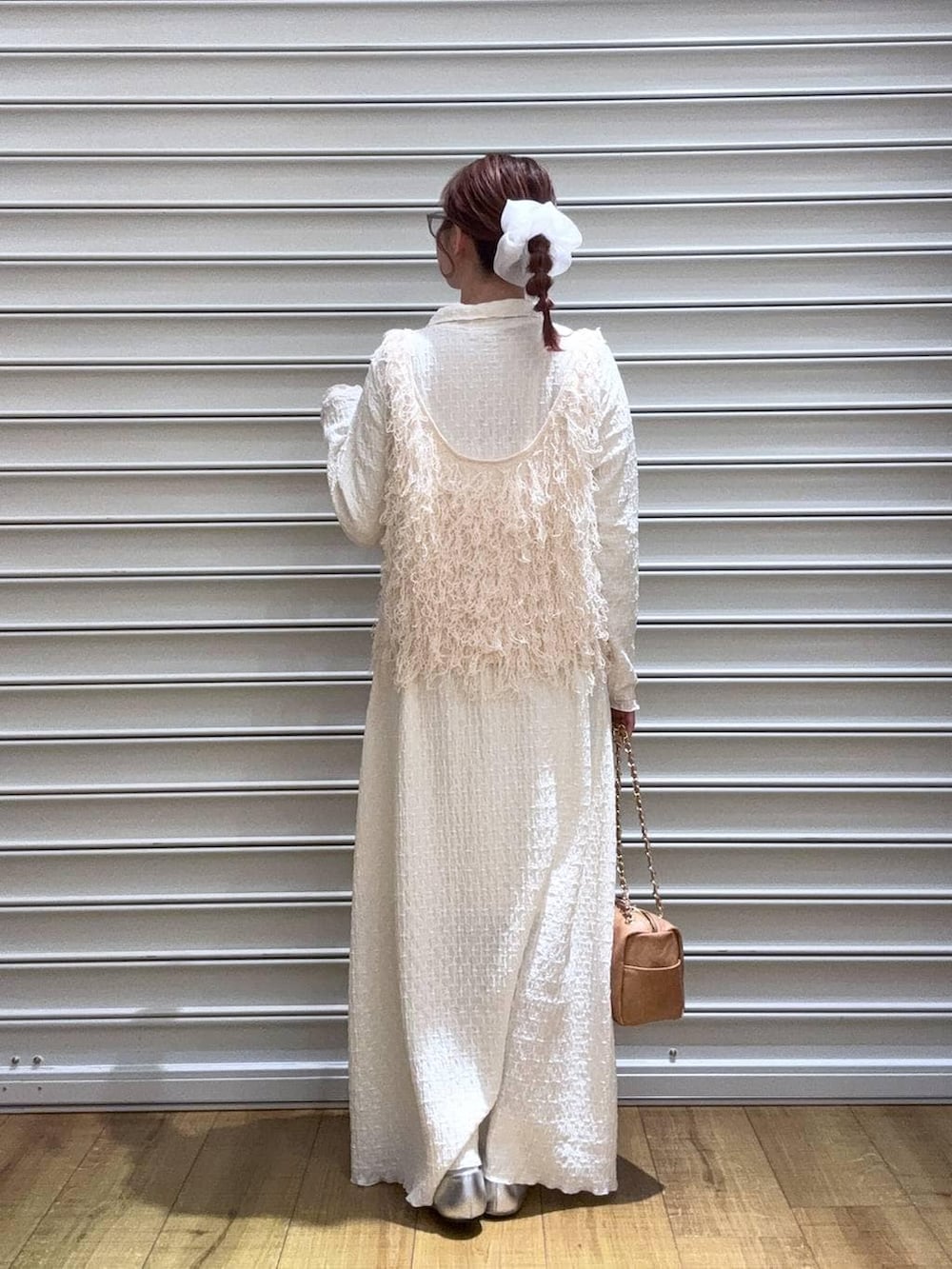 シルバー系のパンプス、ベージュ系のショルダーバッグ、ホワイト系のワンピースを着用したレディースの冬コーディネートの3枚目の写真