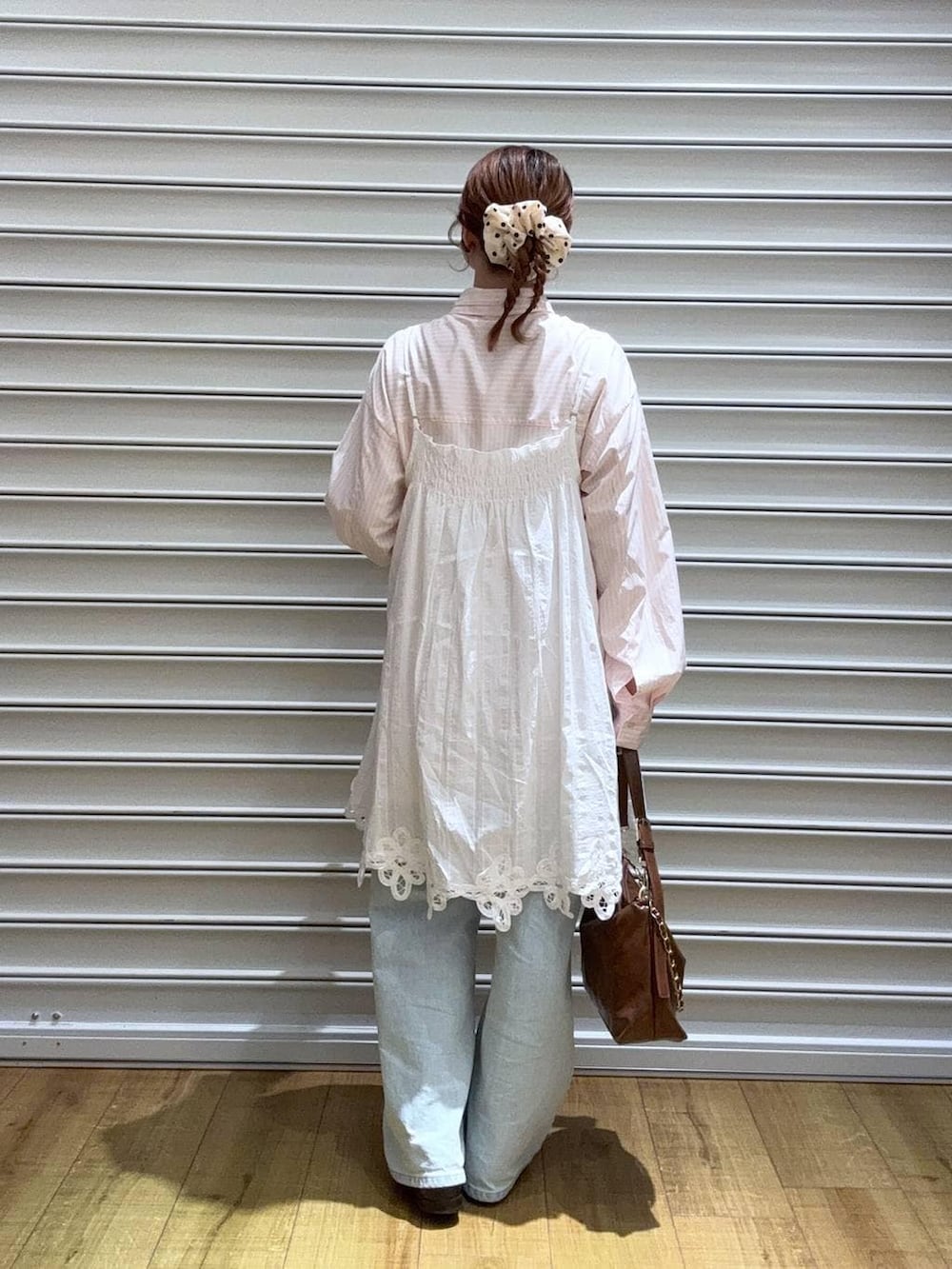 ブルー系のデニムパンツ、ブラウン系のショルダーバッグ、ピンク系のシャツ/ブラウスを着用したレディースの春コーディネートの3枚目の写真