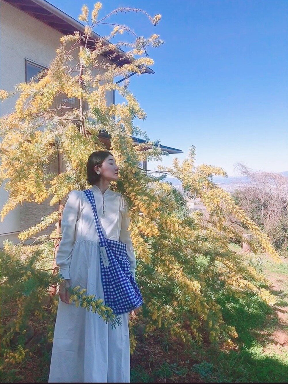 ホワイト系のワンピース、ブルー系のショルダーバッグ、ホワイト系のTシャツ/カットソーを着用したレディースの春コーディネートの2枚目の写真