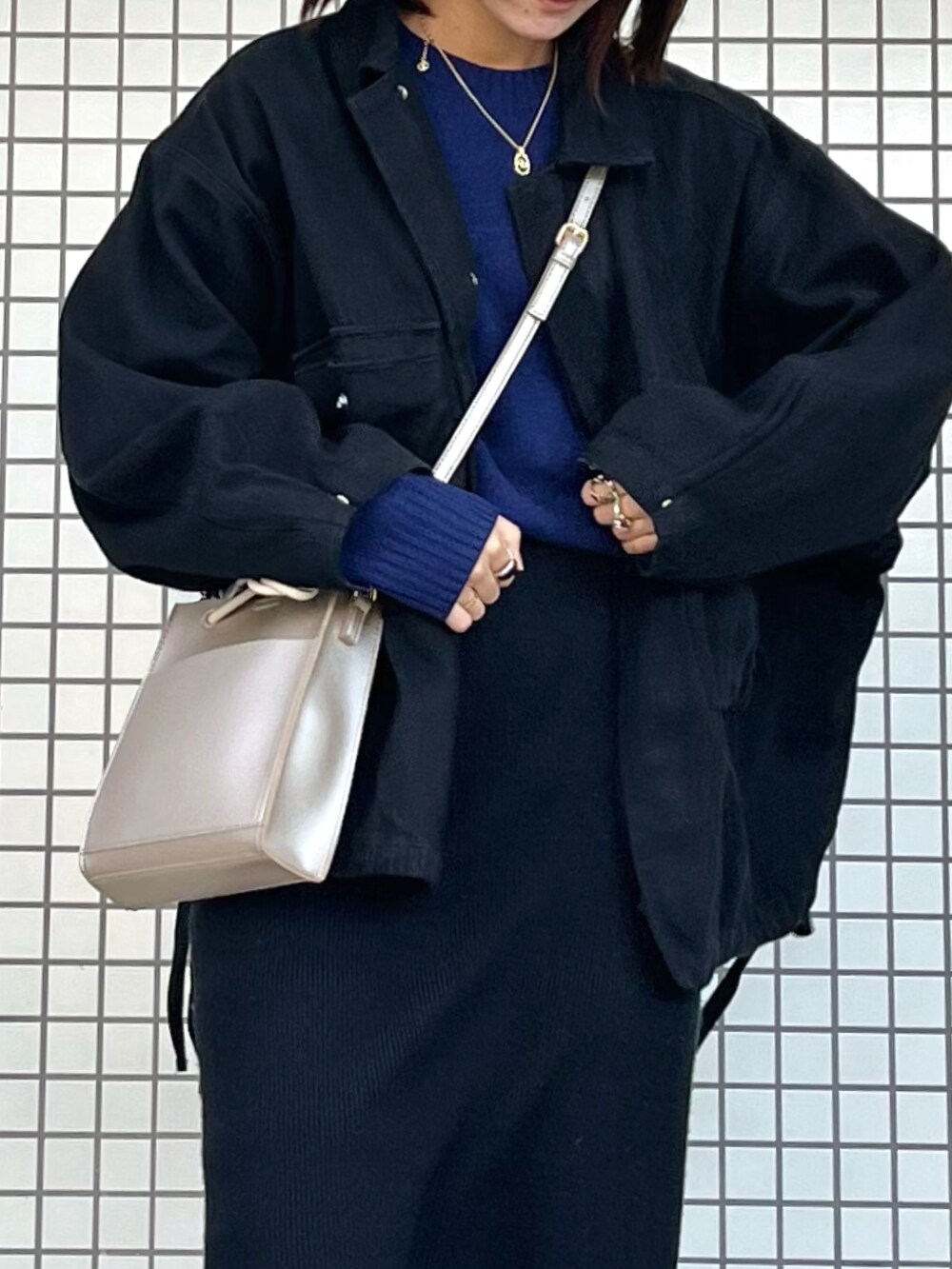 ブラック系のデニムジャケット、ブルー系のニット/セーター、シルバー系のショルダーバッグを着用したレディースの冬コーディネートの3枚目の写真