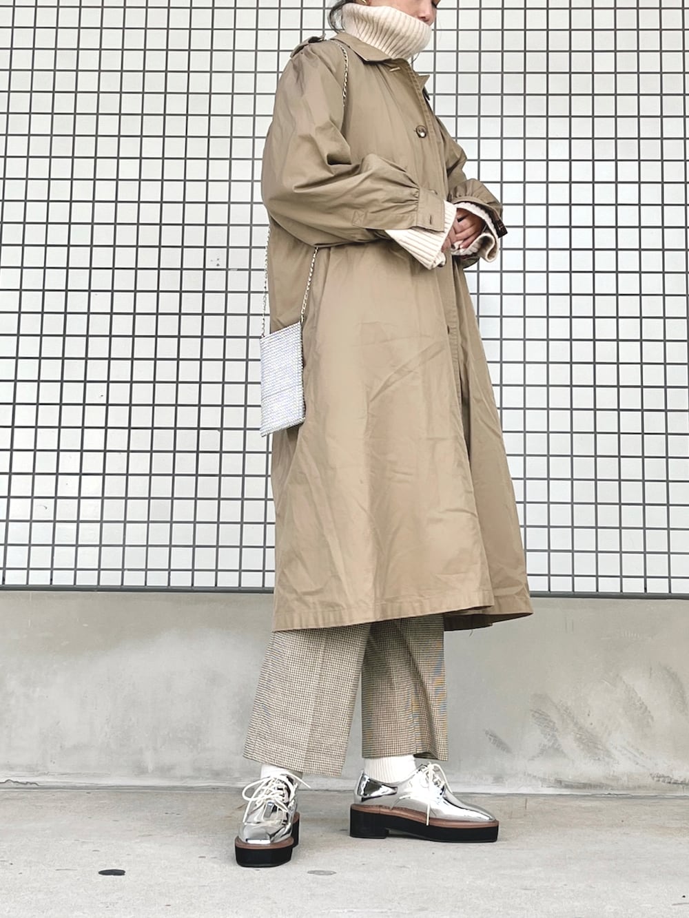 シルバー系のローファー、シルバー系のショルダーバッグ、ホワイト系のニット/セーターを着用したレディースの冬コーディネートの2枚目の写真