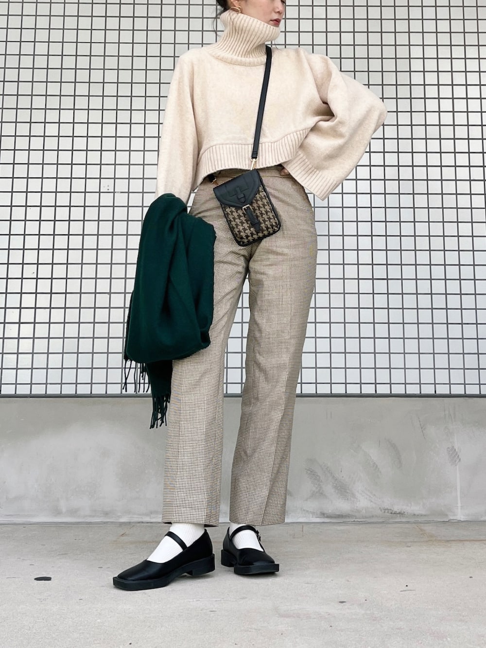 ブラック系のパンプス、ブラック系のショルダーバッグ、ホワイト系のニット/セーターを着用したレディースの冬コーディネートの2枚目の写真