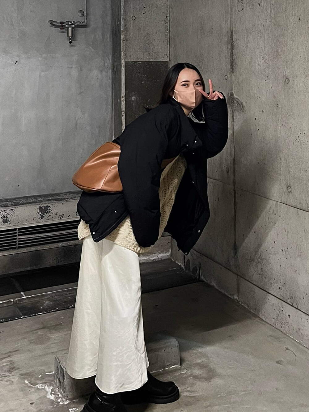 ブラック系のダウンジャケット/コート、ブラウン系のショルダーバッグ、ブラック系のブーツを着用したレディースの冬コーディネートの2枚目の写真