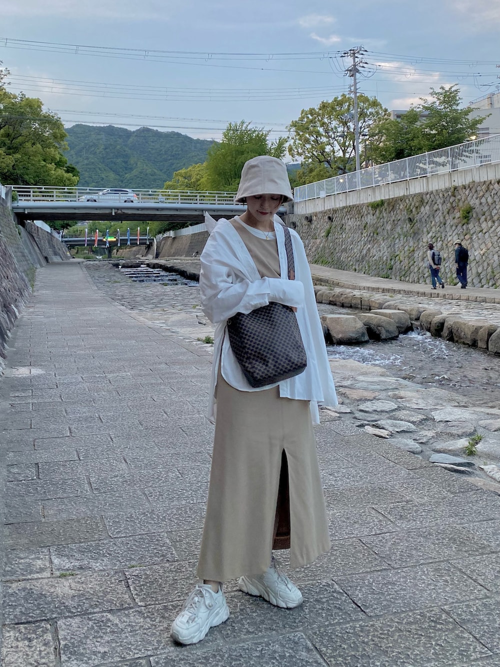 ホワイト系のシャツ/ブラウス、ベージュ系のワンピース/ドレス、ホワイト系のスニーカーを着用したレディースの春コーディネートの2枚目の写真