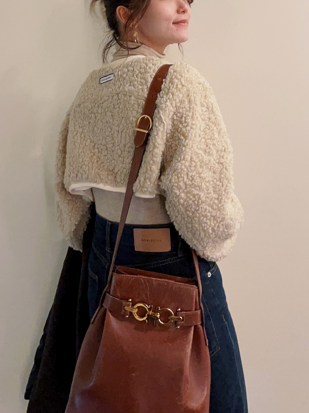 ベージュ系のトップス、ブラウン系のチェスターコート、ブルー系のデニムパンツを着用したレディースの冬コーディネートの2枚目の写真