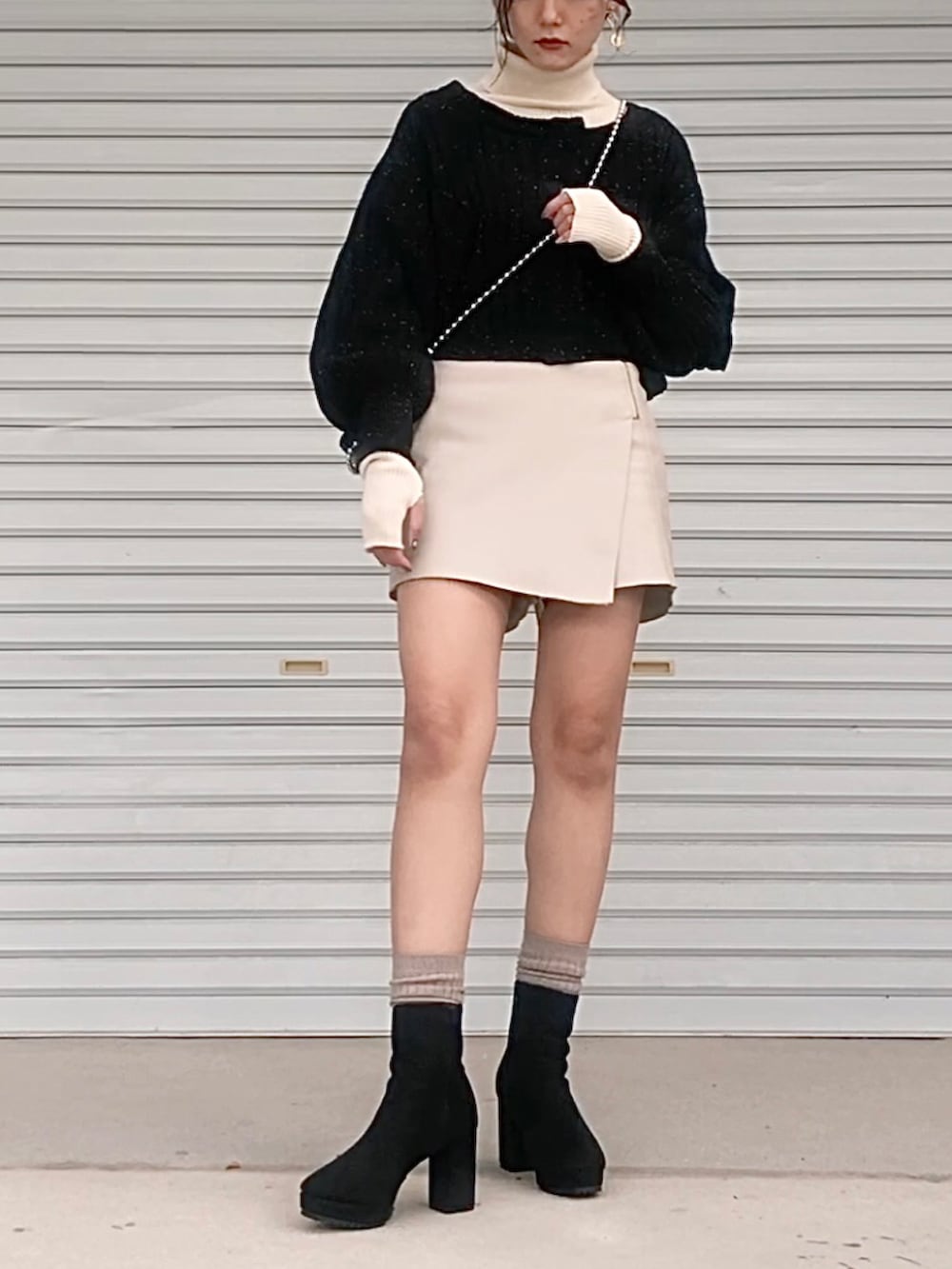 ベージュ系のパンツ、ホワイト系のニット/セーター、ブラック系のブーツを着用したレディースの秋コーディネートの3枚目の写真