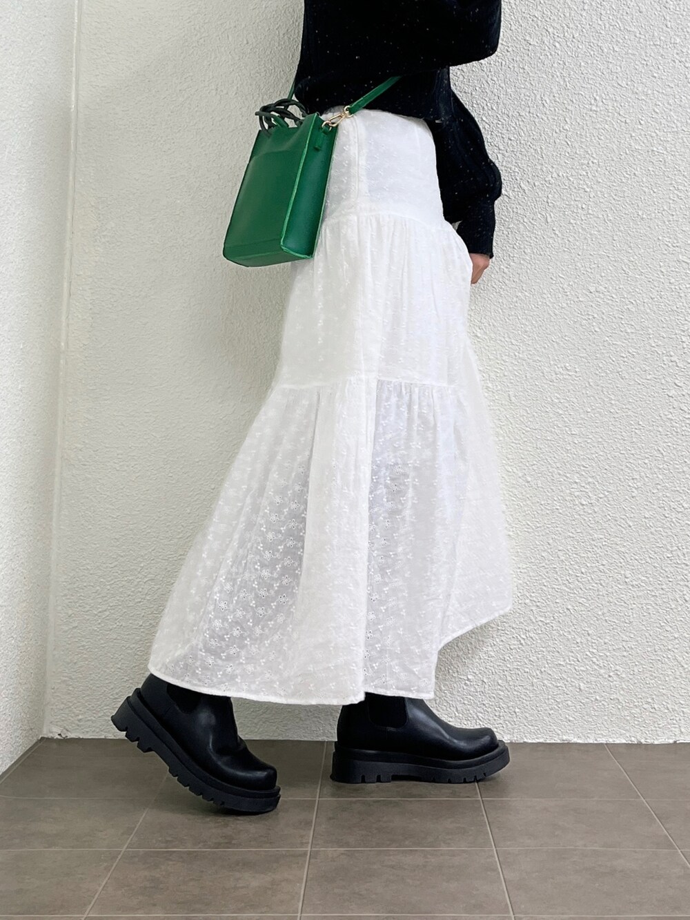 ホワイト系のスカート、グリーン系のショルダーバッグ、ブラック系のブーツを着用したレディースの冬コーディネートの3枚目の写真