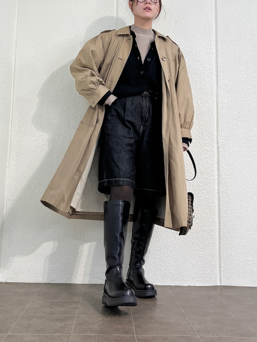 ブラック系のブーツ、ブラック系のショルダーバッグ、ベージュ系のジャケット/アウターを着用したレディースの冬コーディネートの2枚目の写真