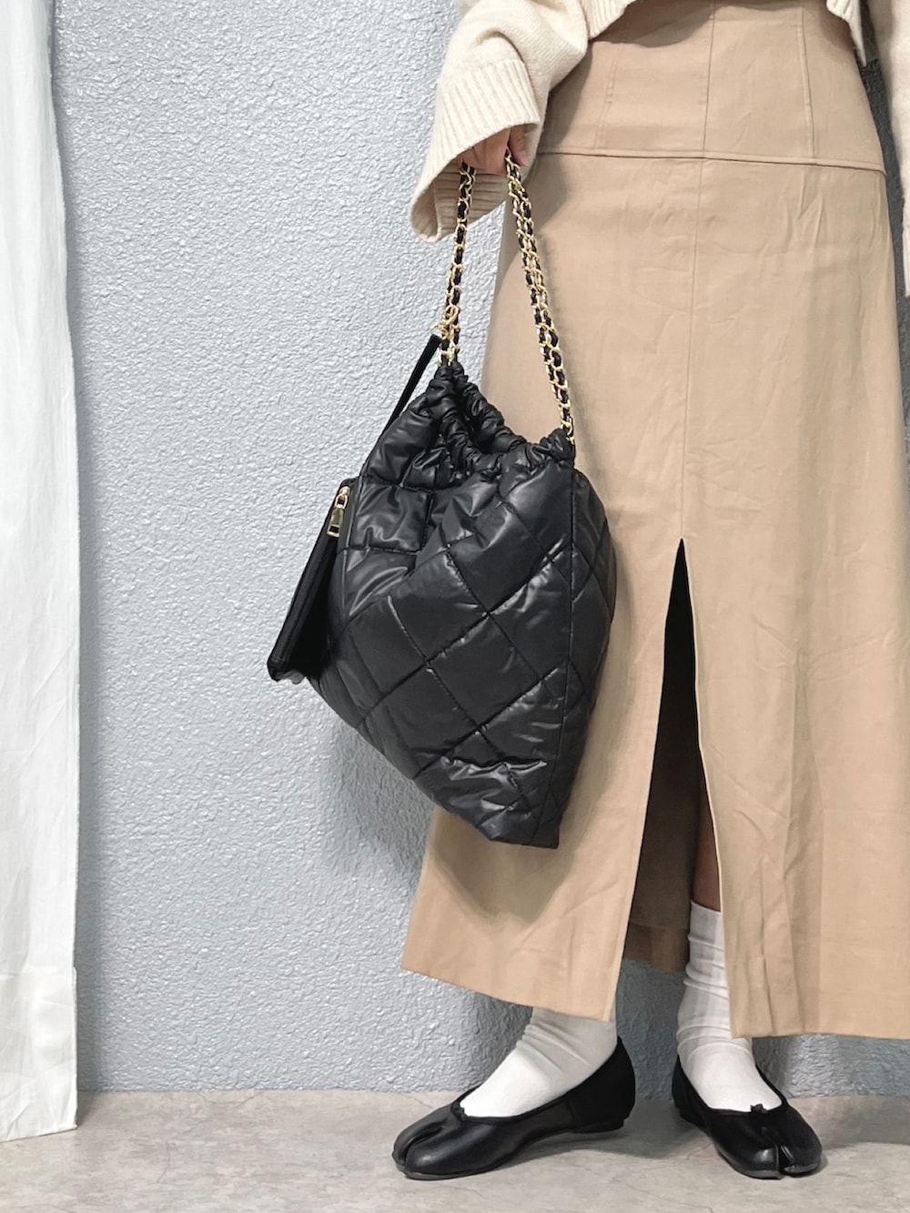 ホワイト系のニット/セーター、ベージュ系のワンピース/ドレス、ブラック系のバッグを着用したレディースの冬コーディネートの3枚目の写真