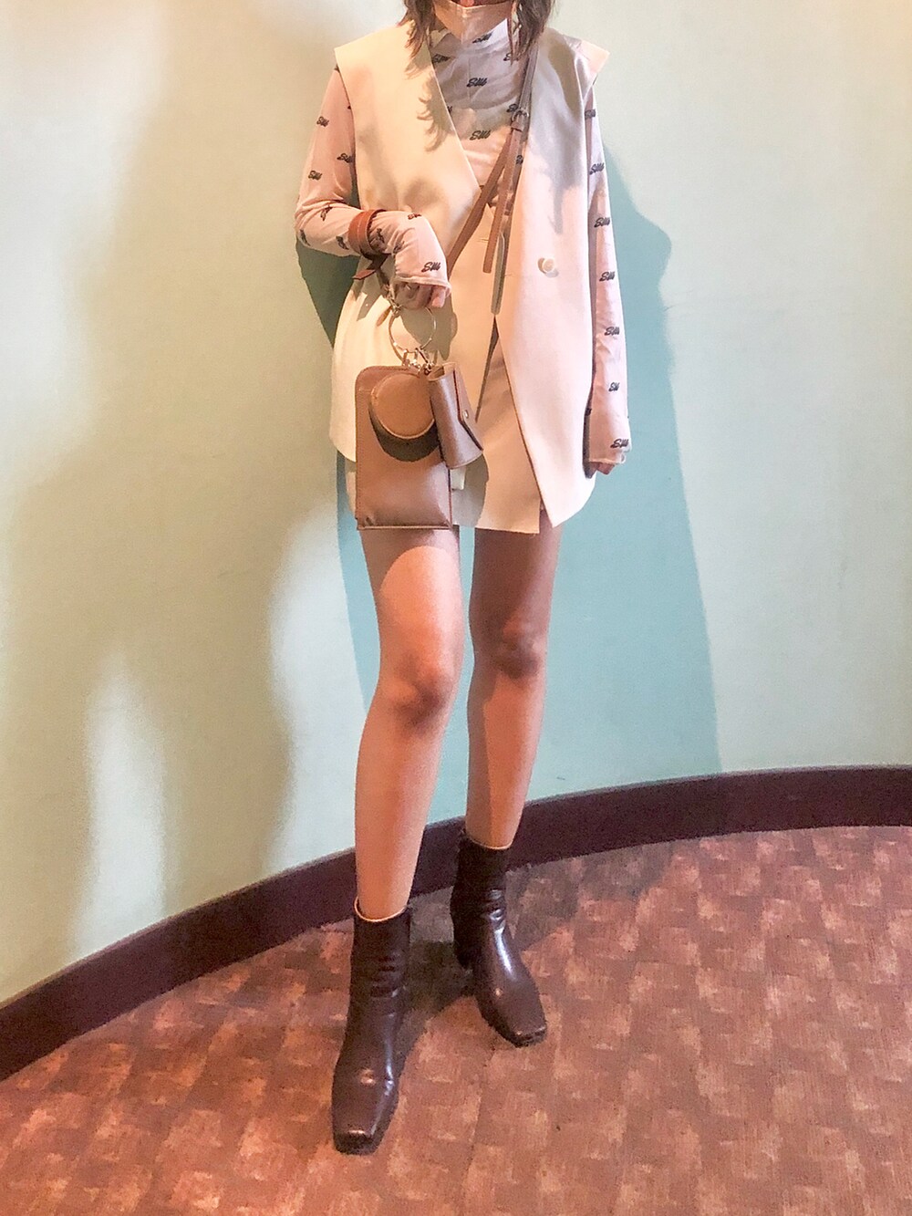 ブラウン系のショルダーバッグ、ホワイト系のベスト、その他のトップスを着用したレディースの秋コーディネートの2枚目の写真