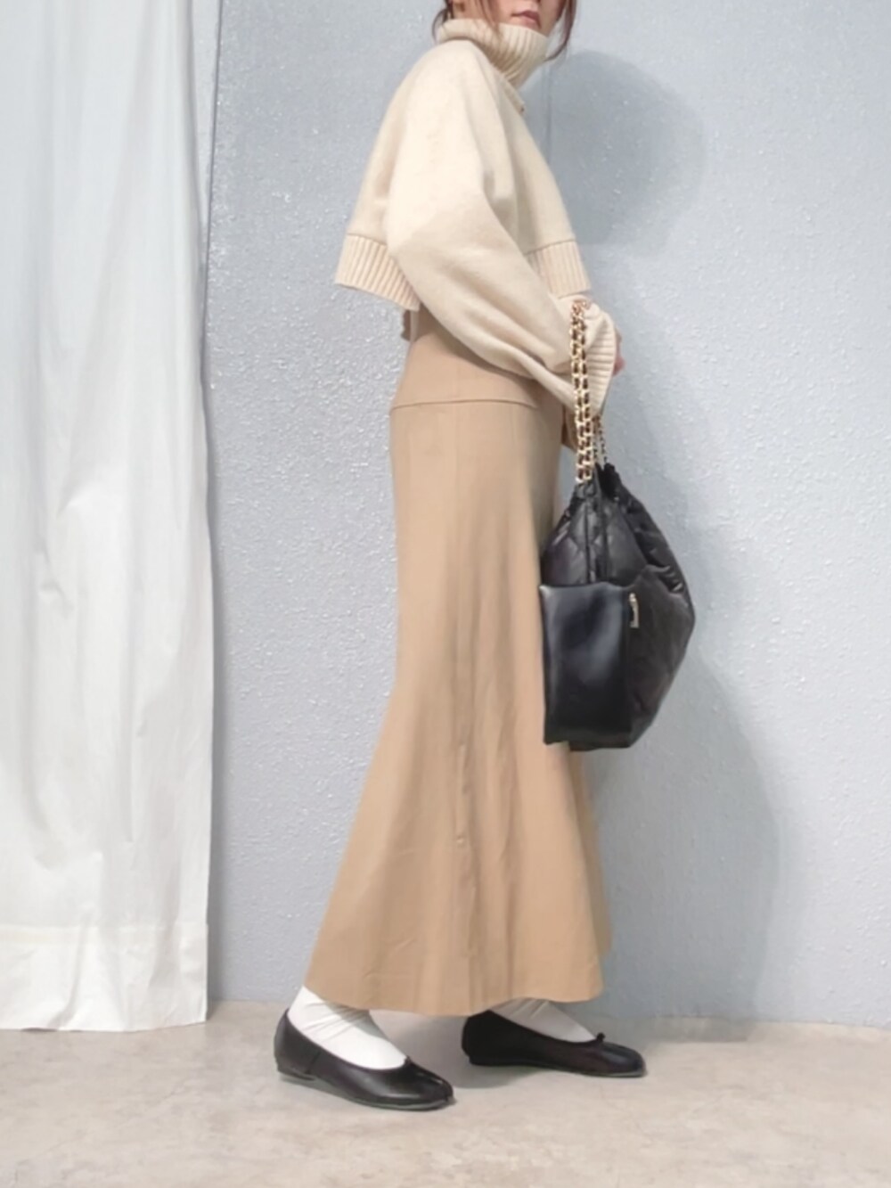 ホワイト系のニット/セーター、ベージュ系のワンピース/ドレス、ブラック系のバッグを着用したレディースの冬コーディネートの2枚目の写真