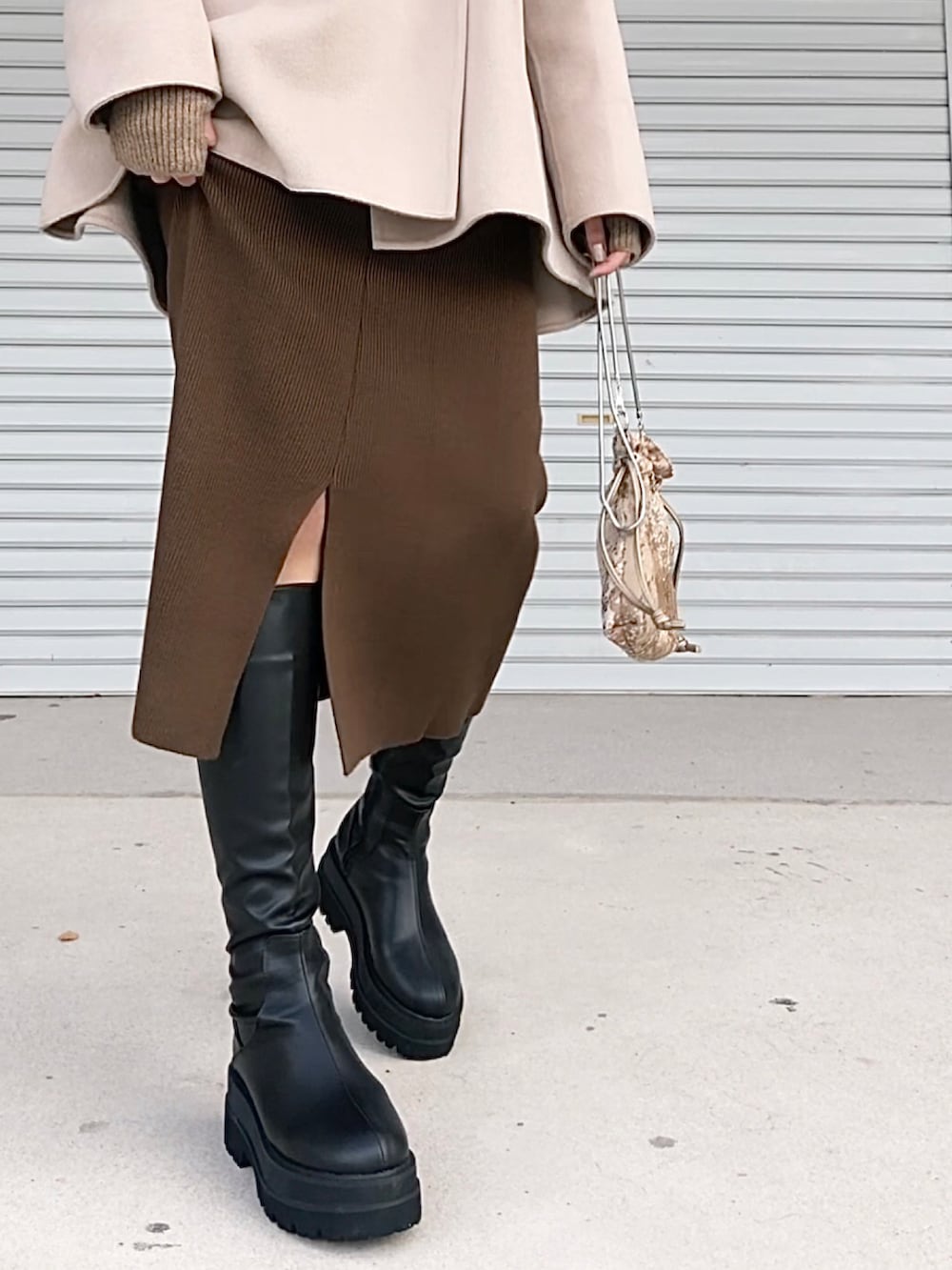 ホワイト系のニット/セーター、ベージュ系のジャケット/アウター、ブラック系のブーツを着用したレディースの秋コーディネートの3枚目の写真