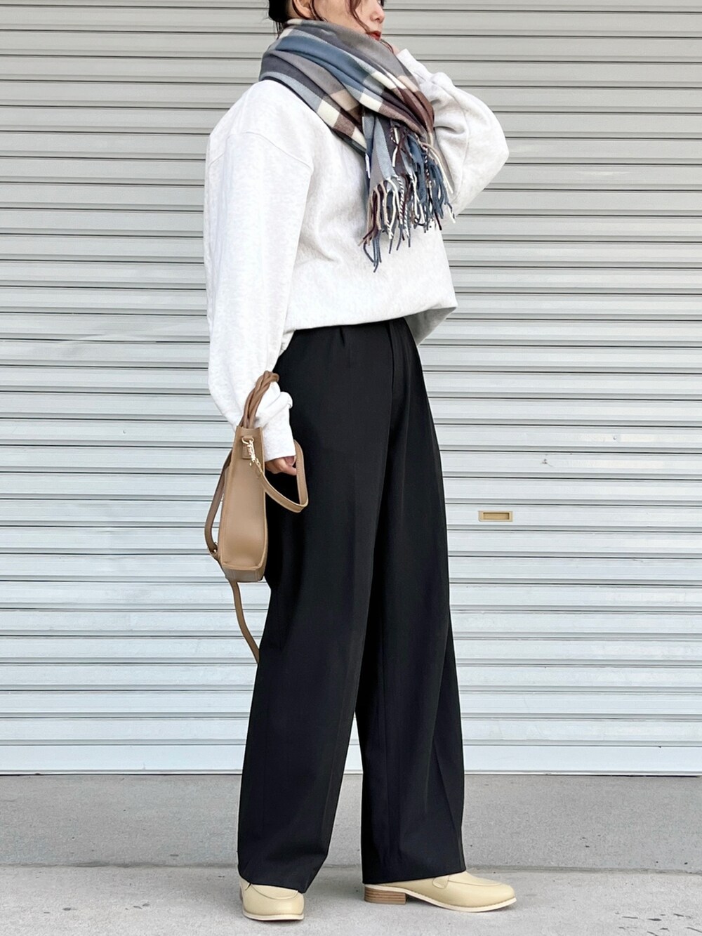 ブラウン系のパンツ、ホワイト系のトップス、ブラウン系のショルダーバッグを着用したレディースの冬コーディネートの2枚目の写真