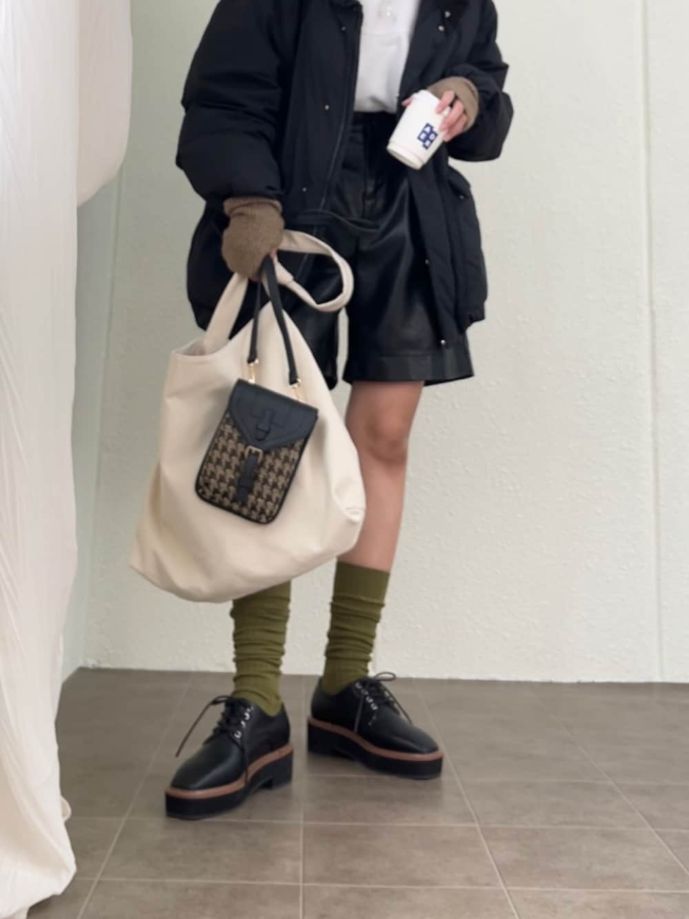 ブラック系のショルダーバッグ、ブラック系のダウンジャケット/コート、ブラック系のローファーを着用したレディースの冬コーディネートの2枚目の写真