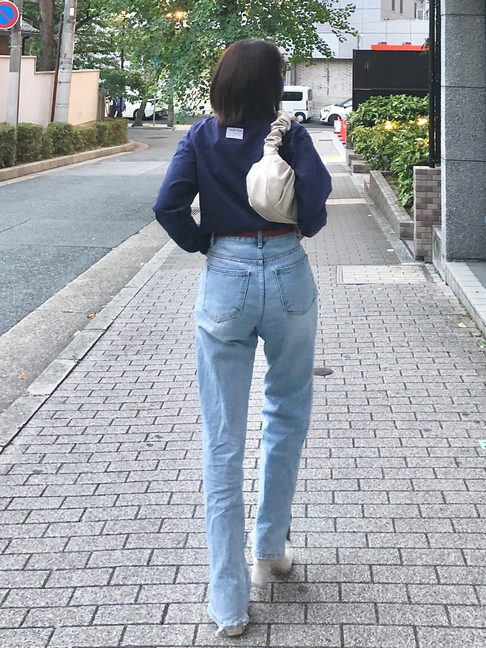 ホワイト系のブーツ、ホワイト系のバッグ、ブルー系のデニムパンツを着用したレディースの秋コーディネートの2枚目の写真