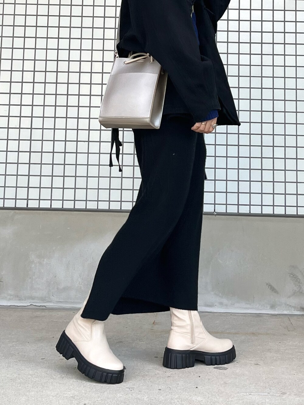 ブラック系のデニムジャケット、ブルー系のニット/セーター、シルバー系のショルダーバッグを着用したレディースの冬コーディネートの2枚目の写真