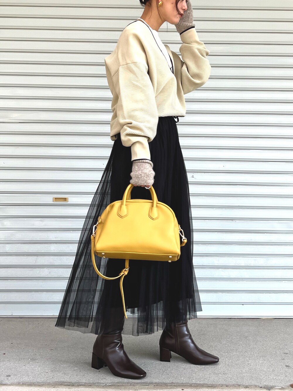 ホワイト系のニット/セーター、ブラック系のスカート、ブラウン系のブーツを着用したレディースの秋コーディネートの3枚目の写真