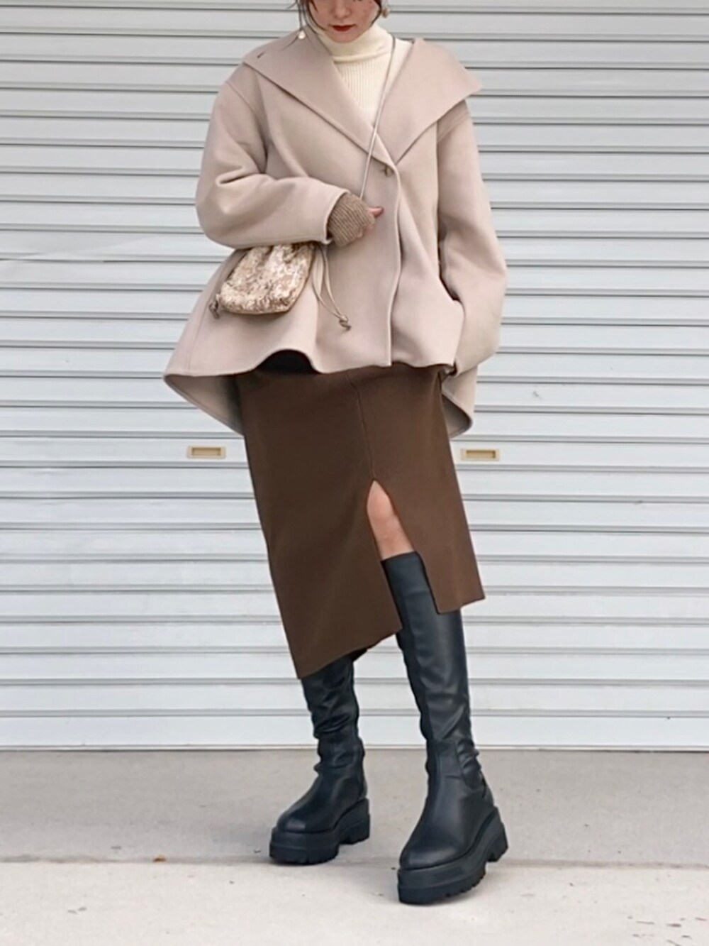 ホワイト系のニット/セーター、ベージュ系のジャケット/アウター、ブラック系のブーツを着用したレディースの秋コーディネートの2枚目の写真
