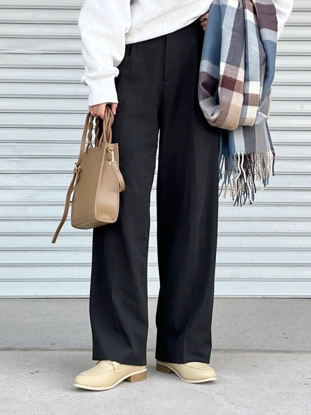 ブラウン系のパンツ、ホワイト系のトップス、ブラウン系のショルダーバッグを着用したレディースの冬コーディネートの3枚目の写真