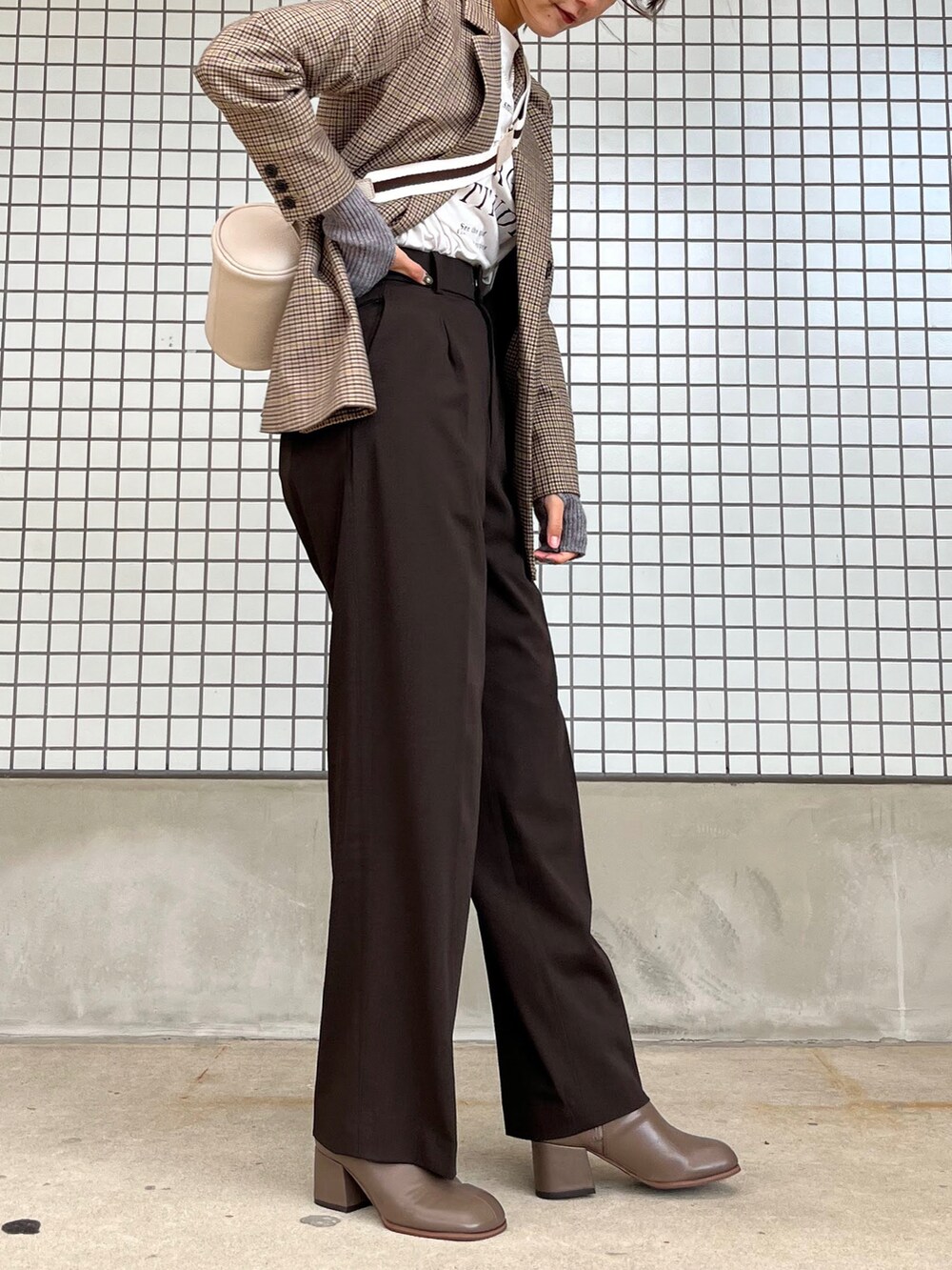 ホワイト系のショルダーバッグ、ベージュ系のブーツ、グレー系のアームカバーを着用したレディースの秋コーディネートの2枚目の写真