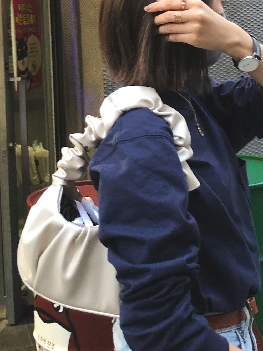 ホワイト系のブーツ、ホワイト系のバッグ、ブルー系のデニムパンツを着用したレディースの秋コーディネートの3枚目の写真