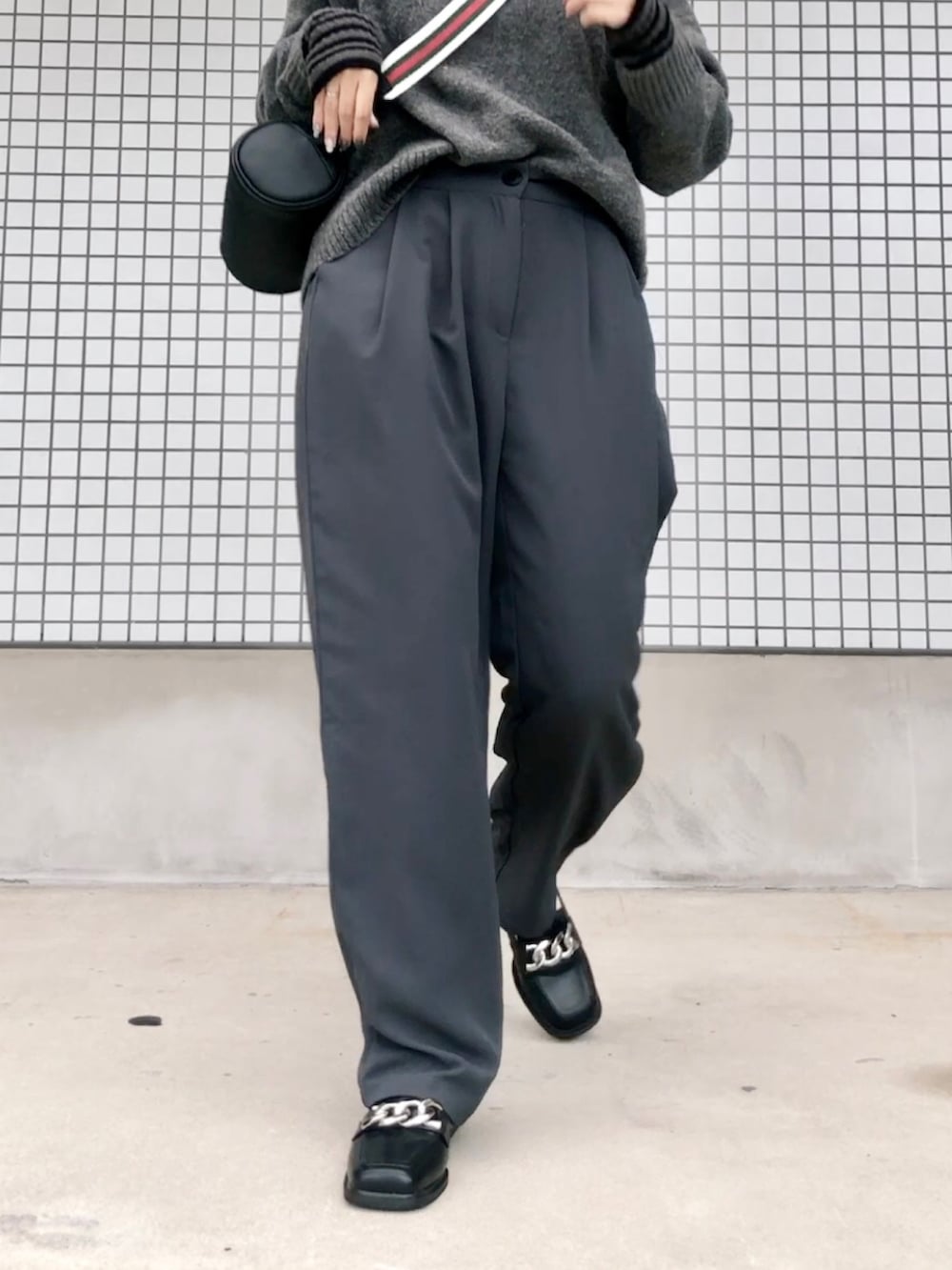 グレー系のニット/セーター、グレー系のパンツ、ブラック系のショルダーバッグを着用したレディースの秋コーディネートの4枚目の写真