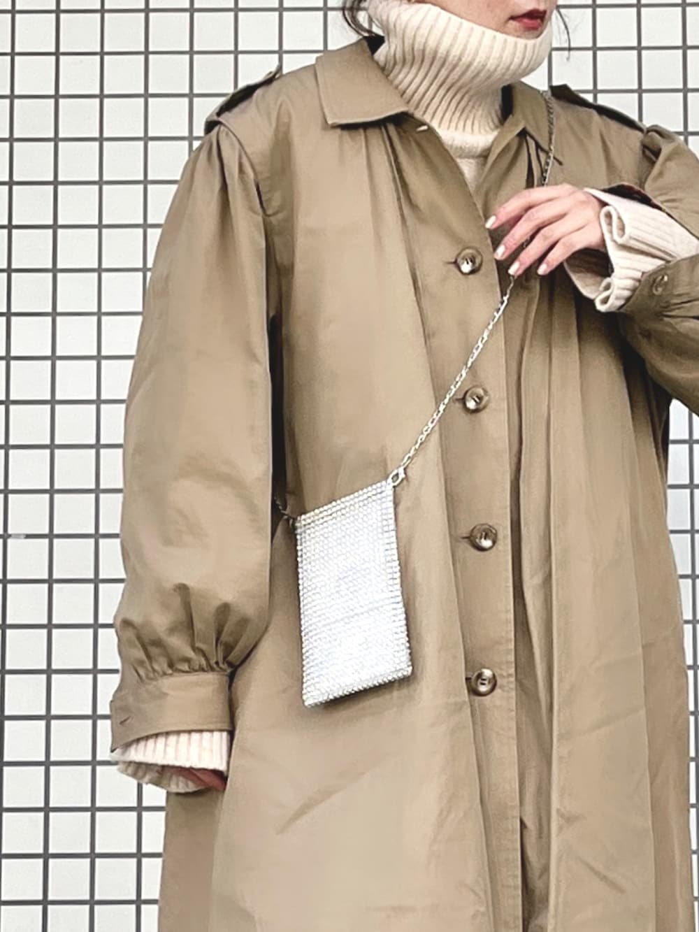 シルバー系のローファー、シルバー系のショルダーバッグ、ホワイト系のニット/セーターを着用したレディースの冬コーディネートの3枚目の写真