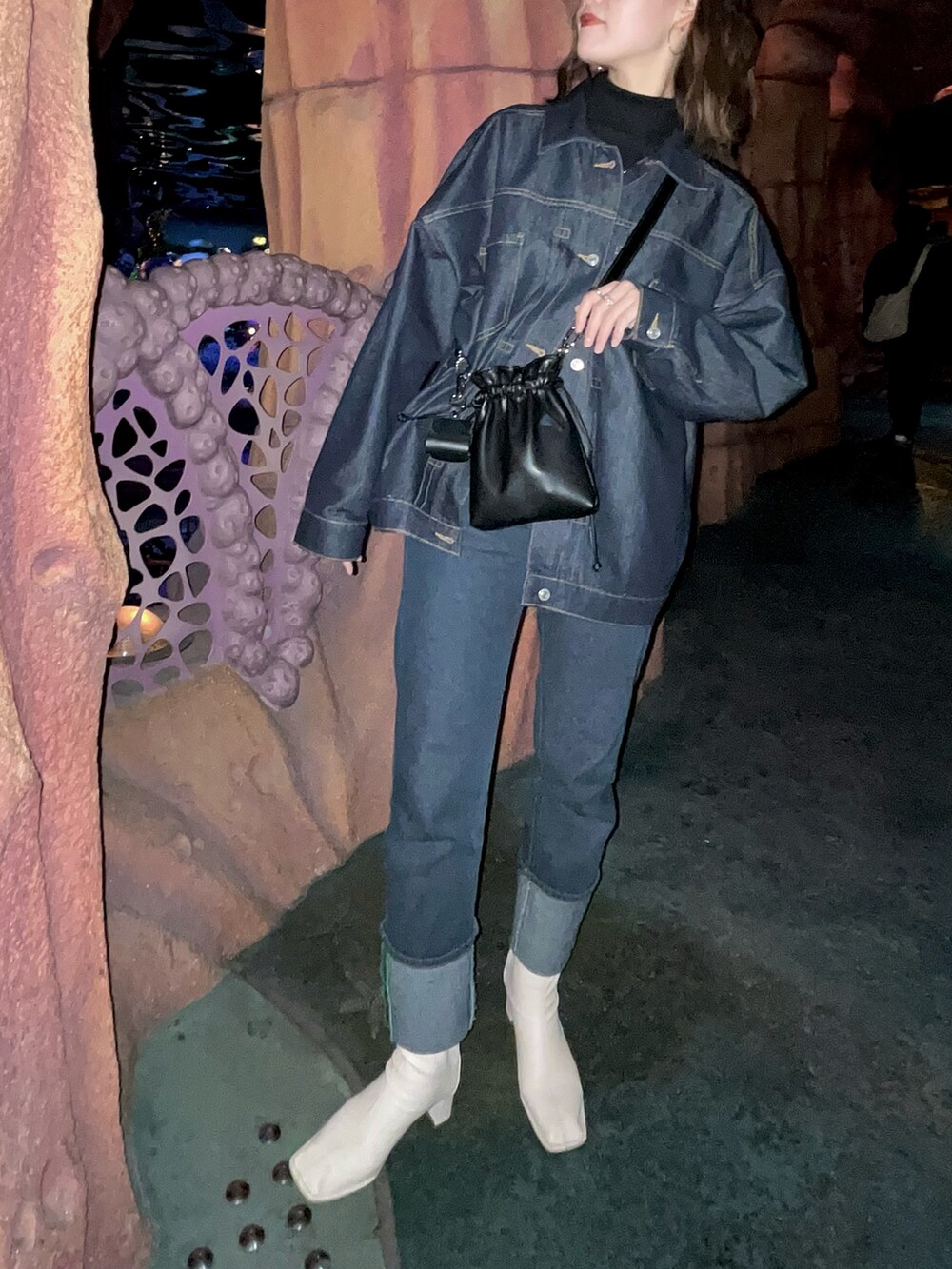 ブラック系のニット/セーター、ブルー系のデニムパンツ、ブラック系のショルダーバッグを着用したレディースの冬コーディネートの2枚目の写真