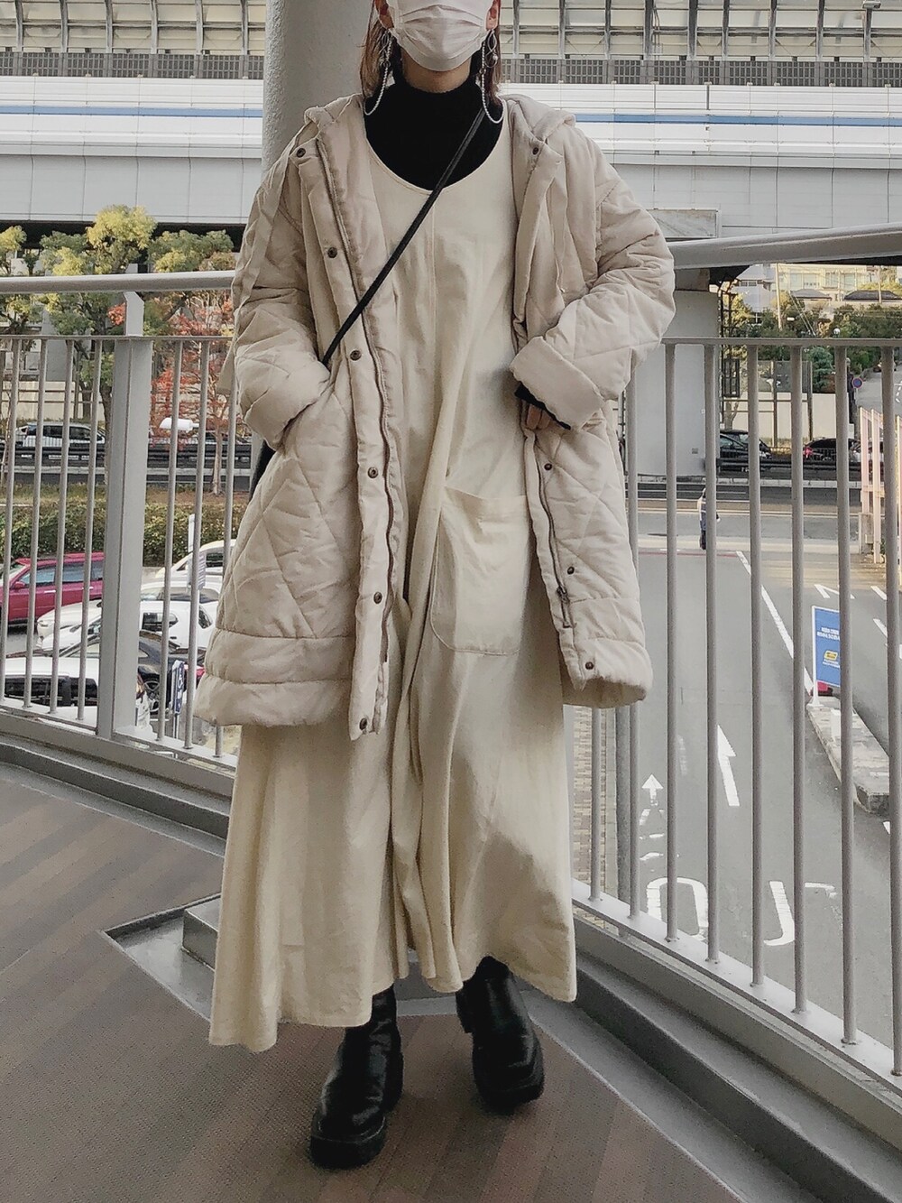 ホワイト系のワンピース、ブラック系のブーツ、ブラック系のニット/セーターを着用したレディースの冬コーディネートの2枚目の写真