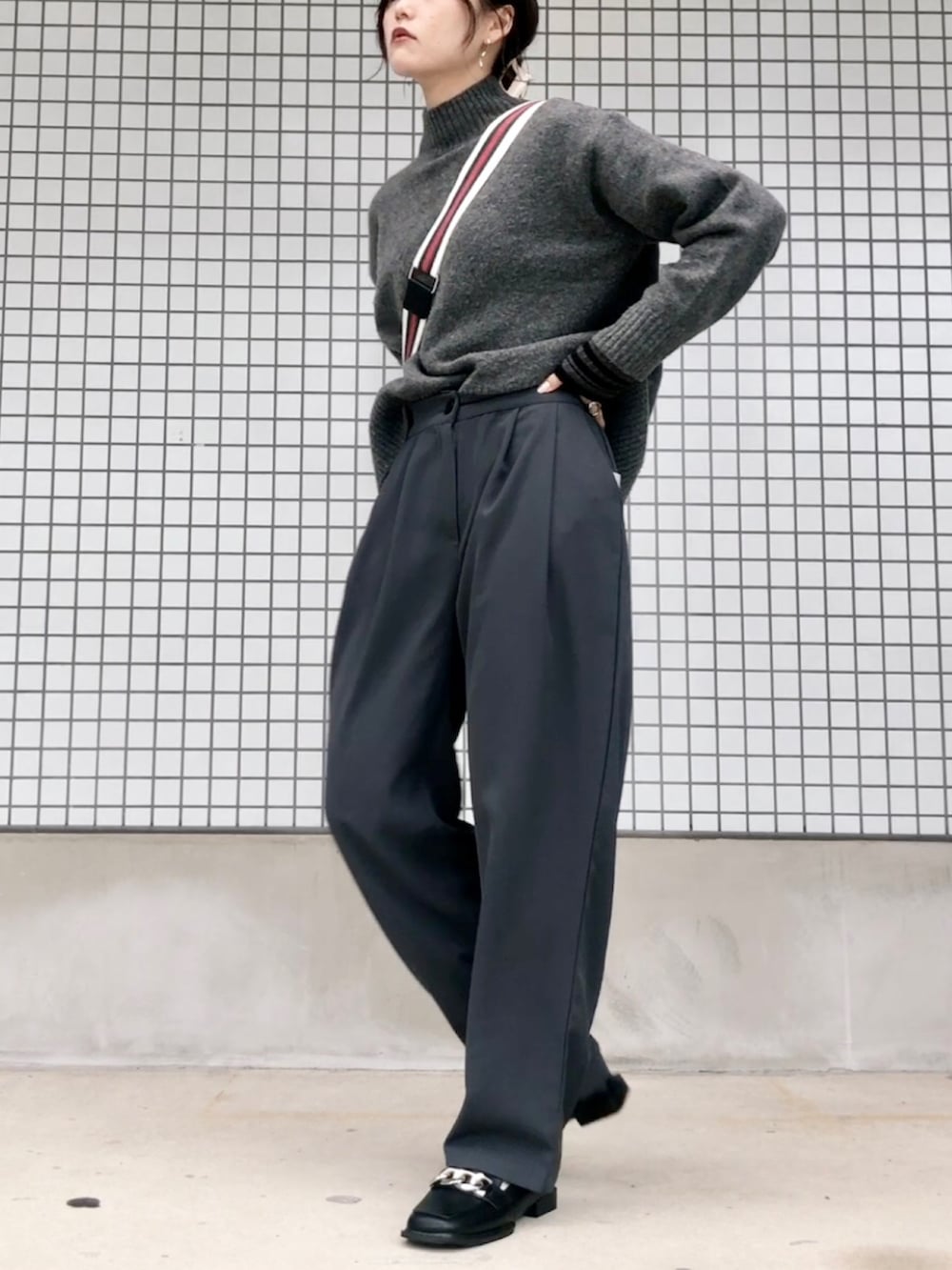 グレー系のニット/セーター、グレー系のパンツ、ブラック系のショルダーバッグを着用したレディースの秋コーディネートの2枚目の写真