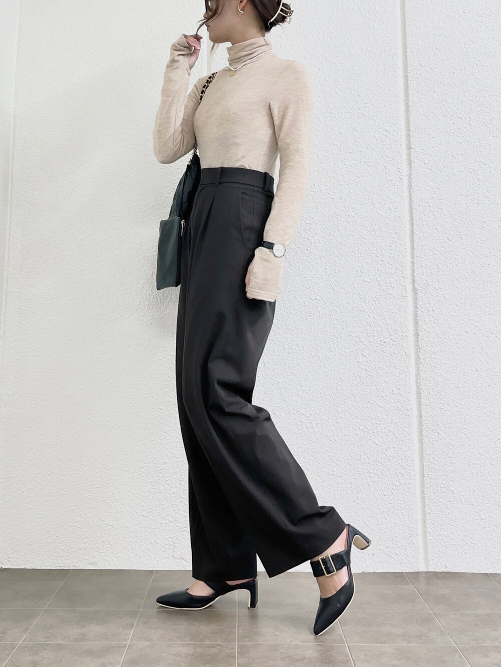 ベージュ系のトップス、ブラウン系のパンツ、ブラック系のバッグを着用したレディースの冬コーディネートの2枚目の写真