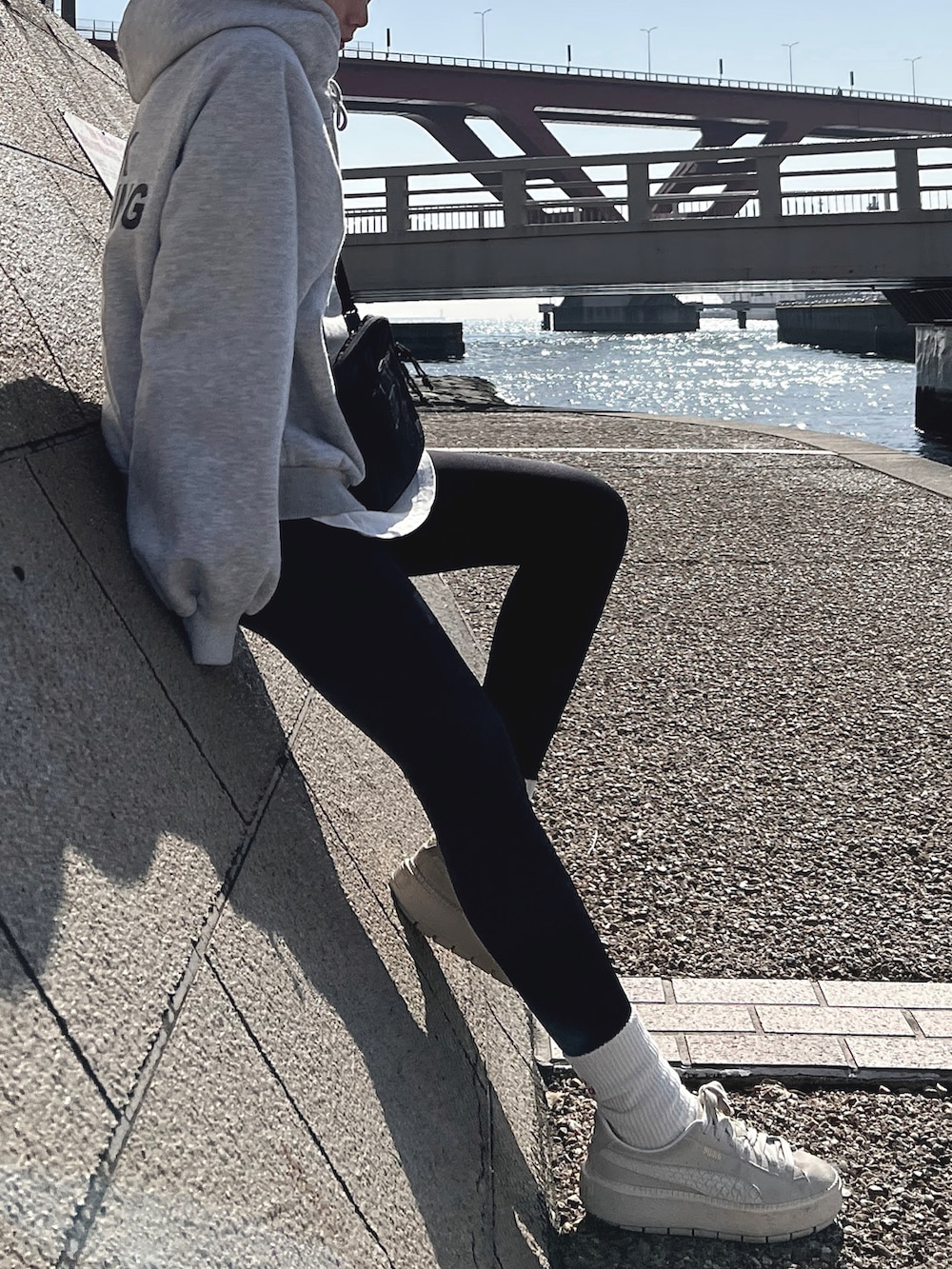 グレー系のトップス、ブラック系のショルダーバッグ、ホワイト系のシューズを着用したレディースの冬コーディネートの2枚目の写真