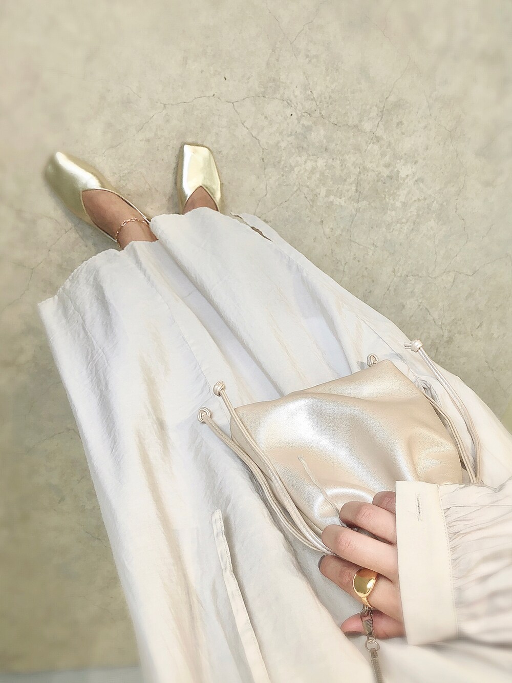 ゴールド系のパンプス、ホワイト系のショルダーバッグを着用したレディースの夏コーディネートの2枚目の写真