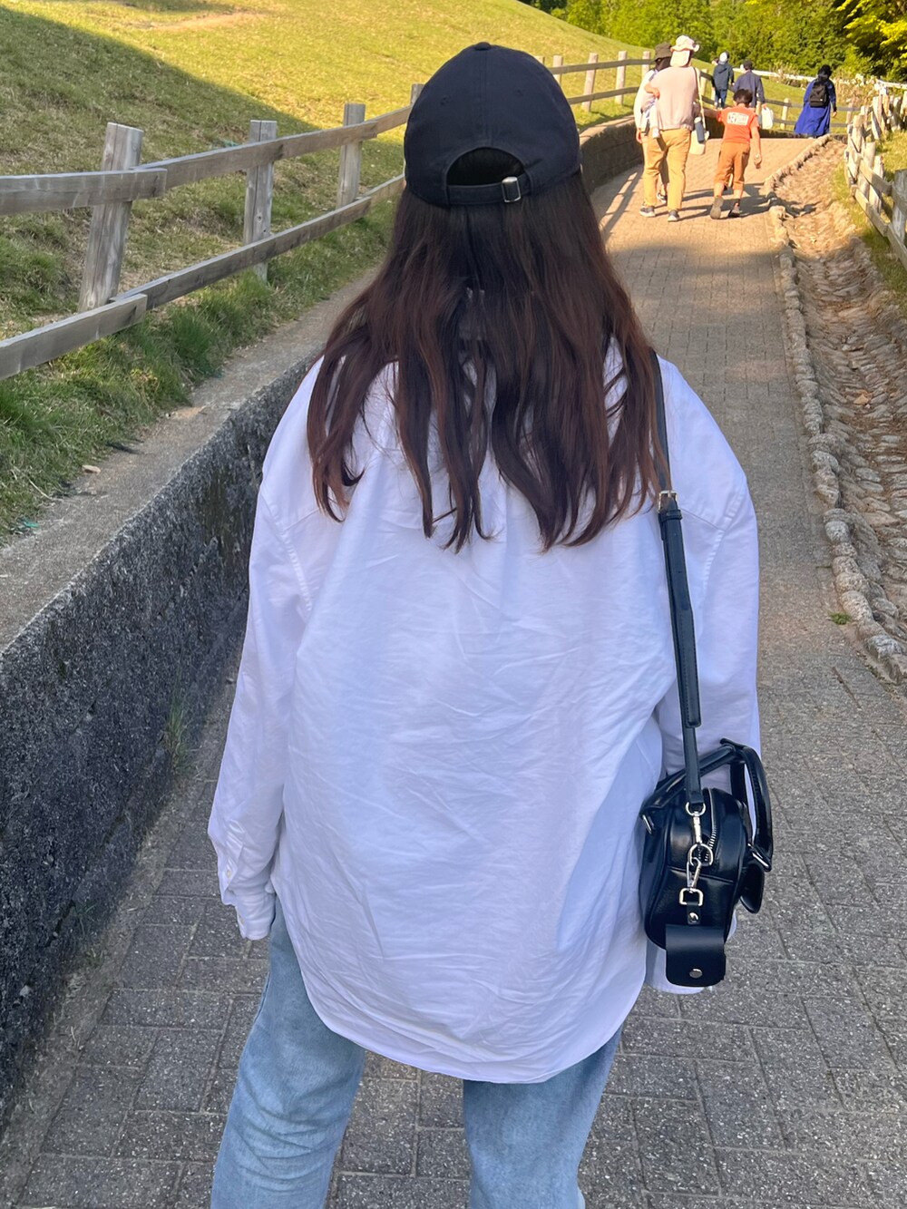 ブルー系のデニムパンツ、ブラック系のショルダーバッグ、ブラック系のパンプスを着用したレディースの春コーディネートの2枚目の写真