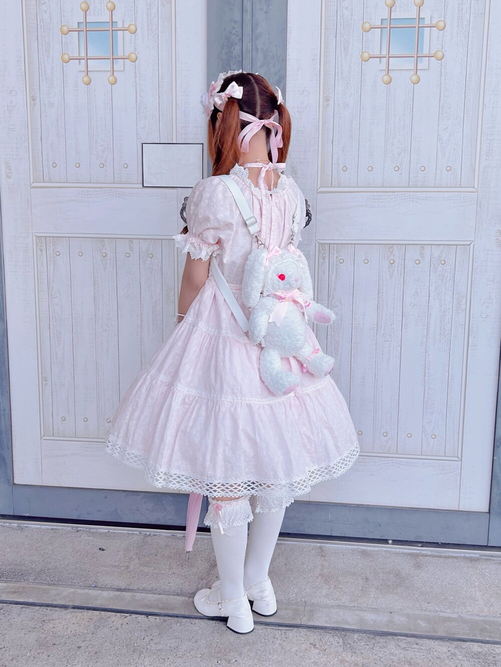 ピンク系のワンピース、ホワイト系のパンプス、ピンク系の長傘を着用したレディースの夏コーディネートの2枚目の写真