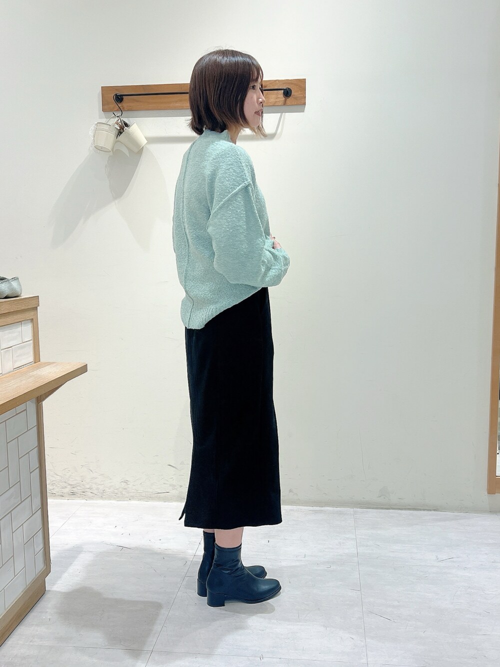 ブラック系のスカート、グリーン系のニット/セーター、ベージュ系のドレスシューズを着用したレディースの秋コーディネートの2枚目の写真