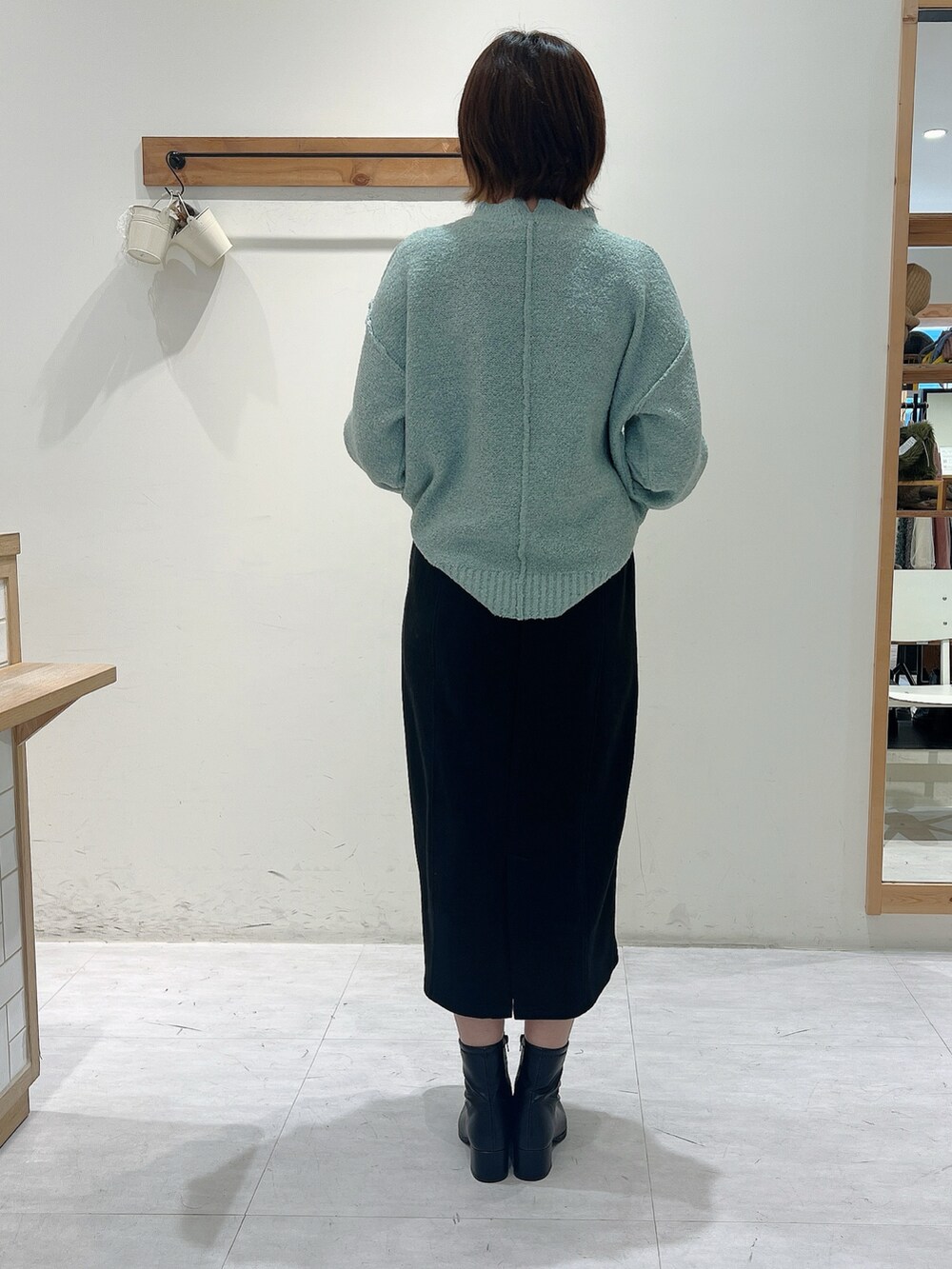 ブラック系のスカート、グリーン系のニット/セーター、ベージュ系のドレスシューズを着用したレディースの秋コーディネートの3枚目の写真