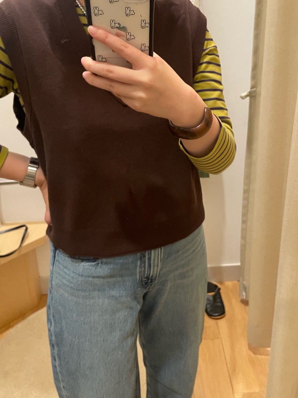 ブルー系のデニムパンツ、ブラウン系のベスト、イエロー系のTシャツ/カットソーを着用したレディースの秋コーディネートの5枚目の写真