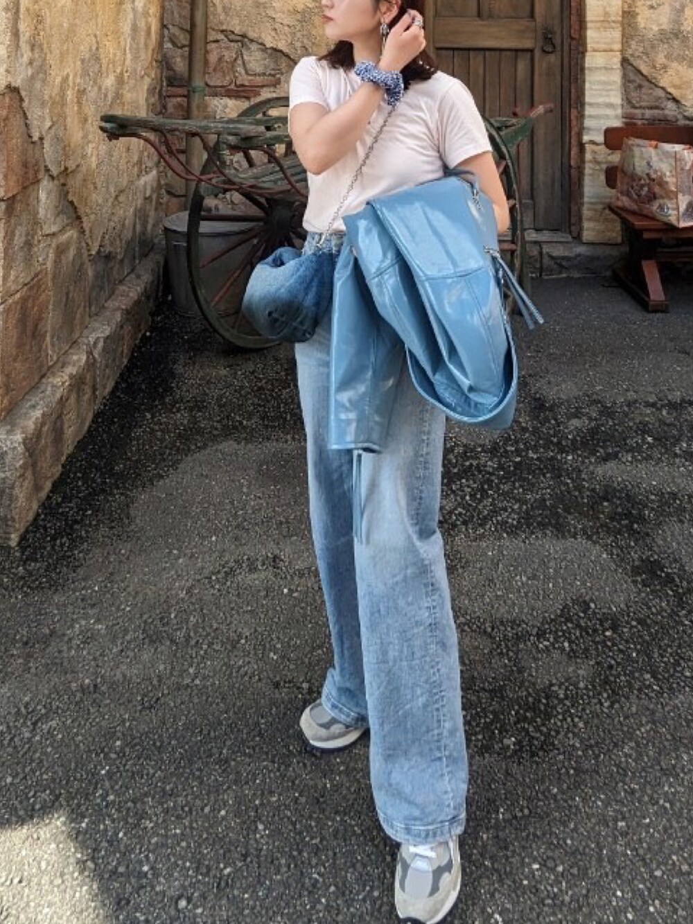 ブルー系のライダースジャケット、ブルー系のショルダーバッグ、ブルー系のデニムパンツを着用したレディースの秋コーディネートの3枚目の写真