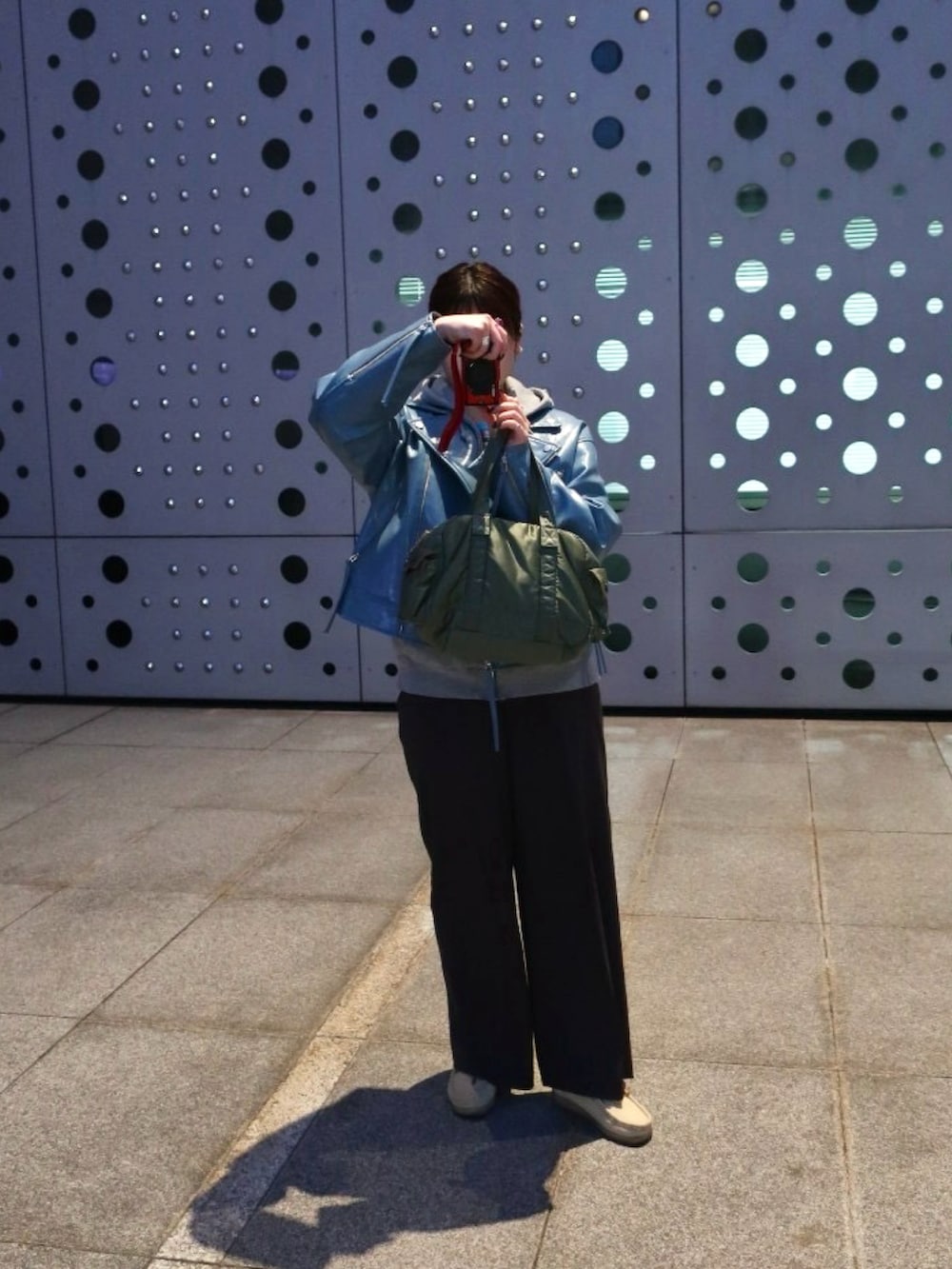 グレー系のパンツ、ベージュ系のモカシン/デッキシューズ、ブルー系のライダースジャケットを着用したレディースの春コーディネートの2枚目の写真