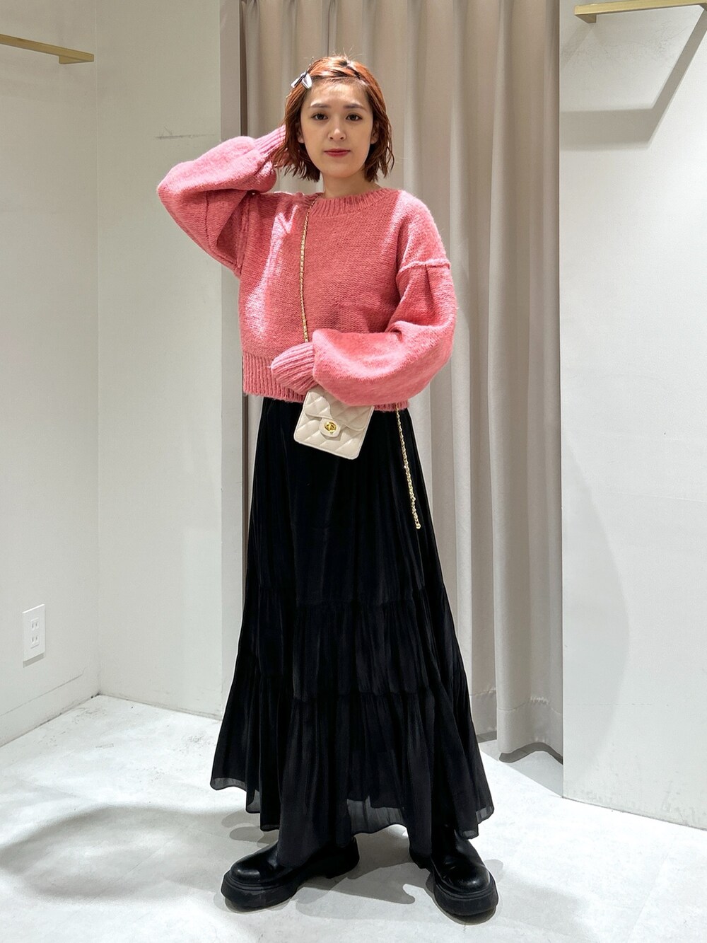ピンク系のニット/セーター、ブラック系のスカート、ホワイト系のショルダーバッグを着用したレディースの冬コーディネートの2枚目の写真