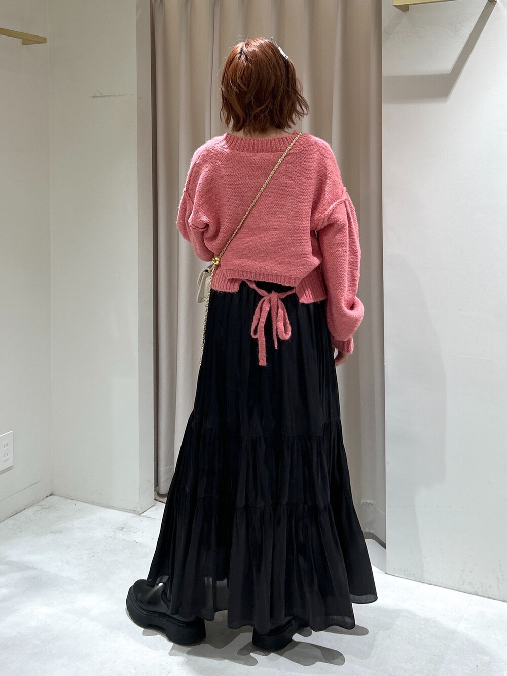 ピンク系のニット/セーター、ブラック系のスカート、ホワイト系のショルダーバッグを着用したレディースの冬コーディネートの4枚目の写真