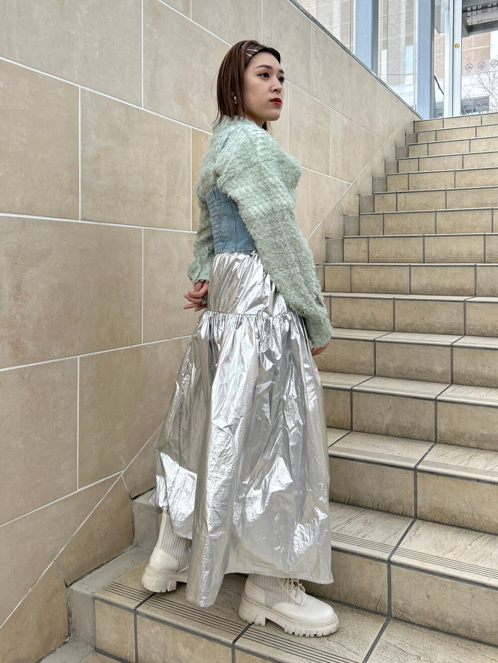 ブルー系のベスト、グリーン系のシャツ/ブラウス、シルバー系のスカートを着用したレディースの春コーディネートの2枚目の写真