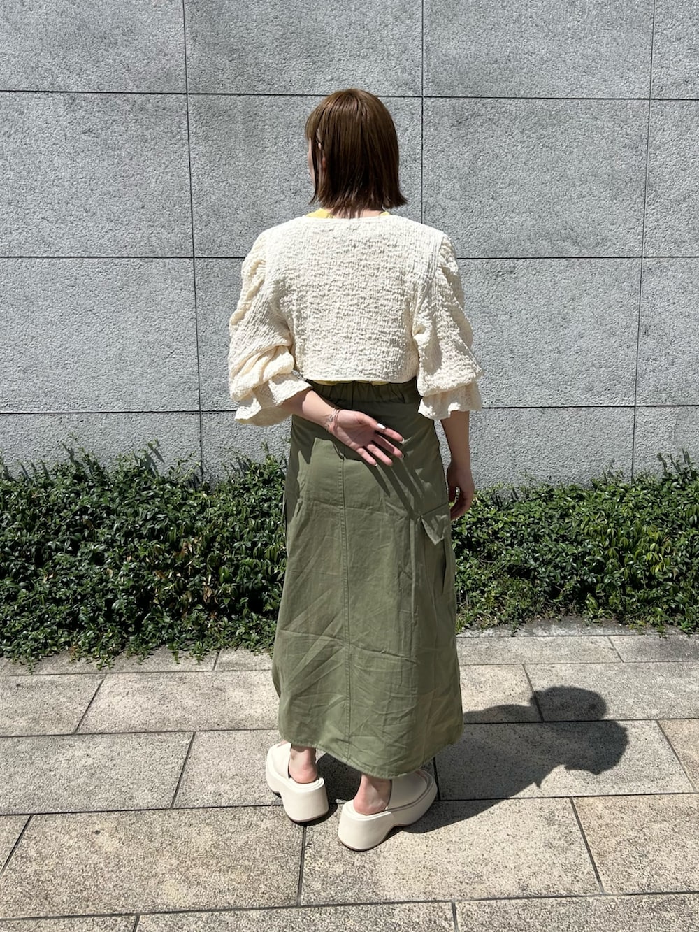 グリーン系のスカート、ホワイト系のサンダル、ホワイト系のシャツ/ブラウスを着用したレディースの夏コーディネートの2枚目の写真